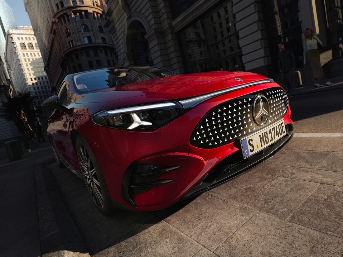 Der neue vollelektrische CLA 250+ von Mercedes-Benz front Ansicht mit einer Frau an der Seite stehend und einem roten Vorhang im Hintergrund