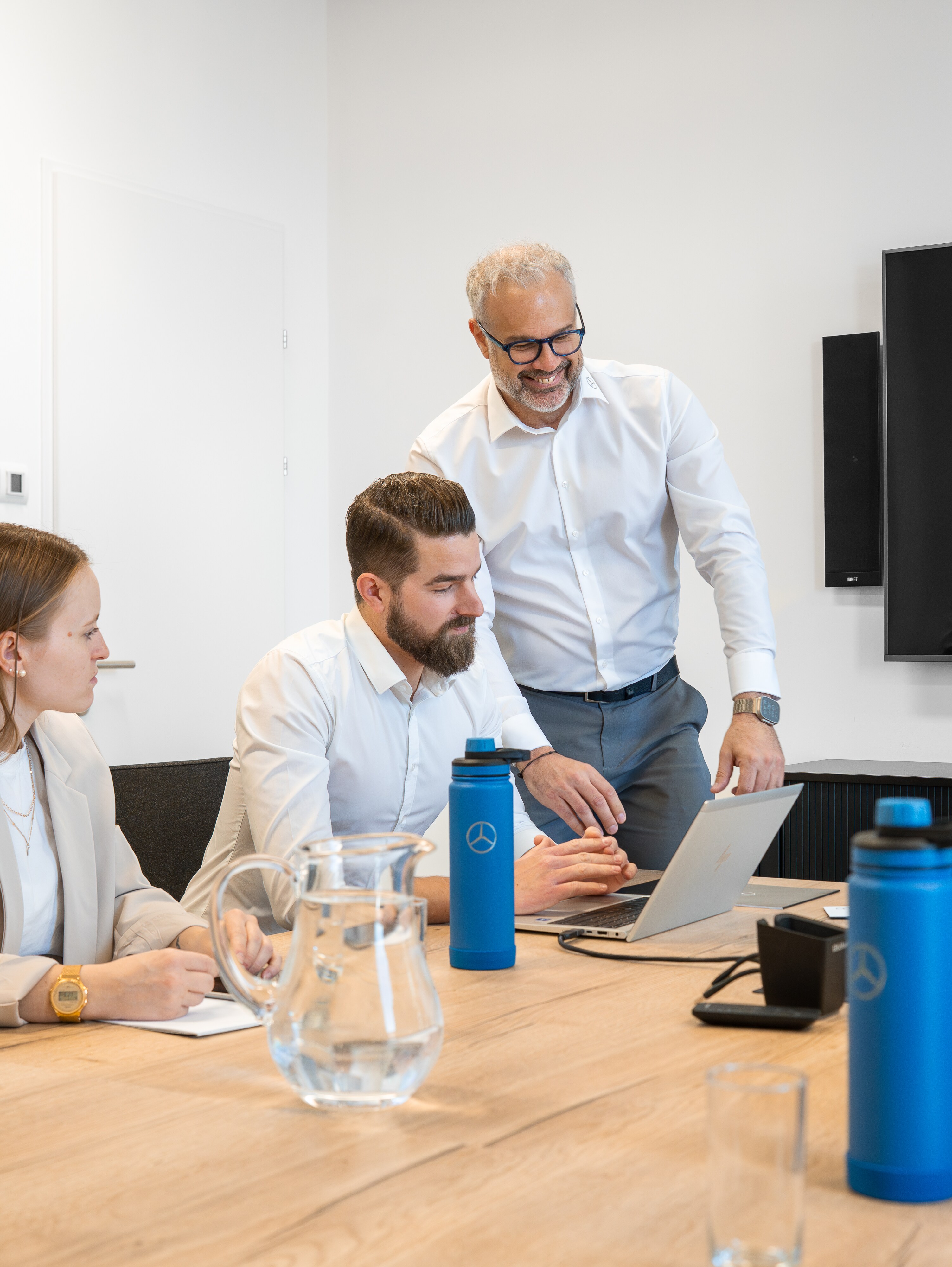 Drei Personen die an einem Tisch sitzen und ein Meeting abhalten.