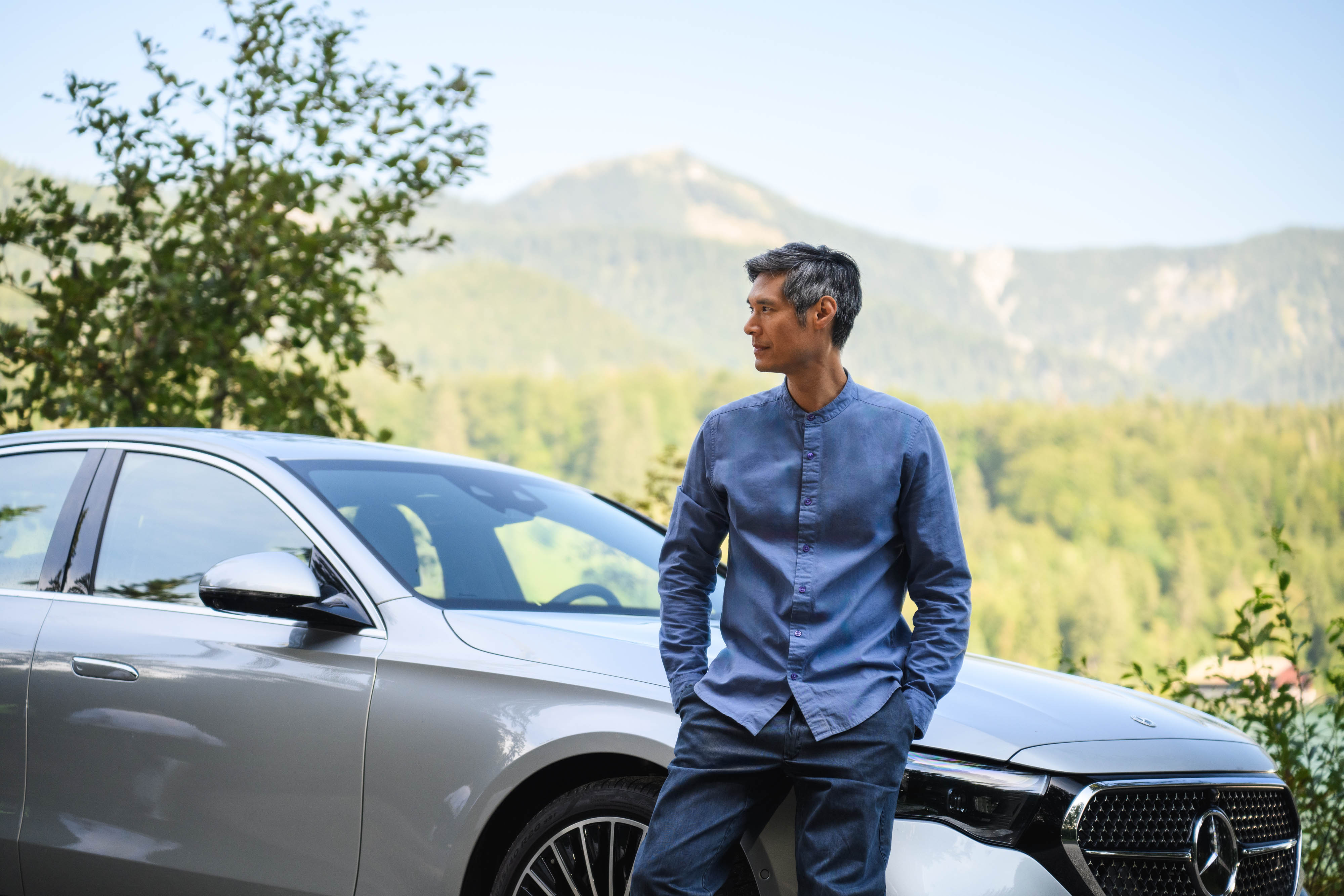 Versicherung | Financial Services | Mercedes-Benz Eine Person steht mit ihrem Mercedes-Benz in der Natur und blickt in die Ferne.