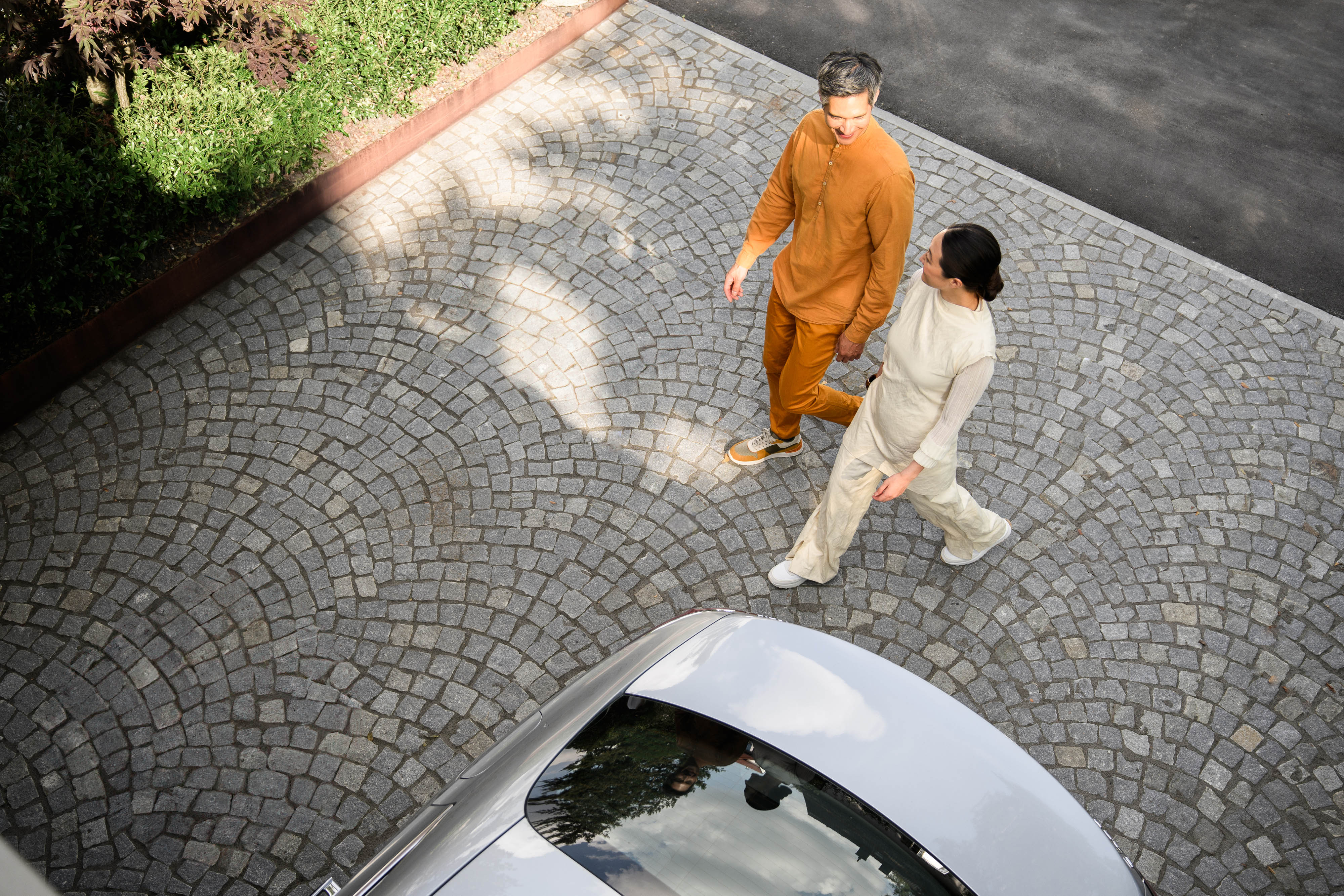 Mieten | Finanzierung | Financial Services | Mercedes-Benz Eine Aufnahme aus hoher Perspektive von zwei Personen, die auf ein Mercedes-Benz Fahrzeug zugehen.