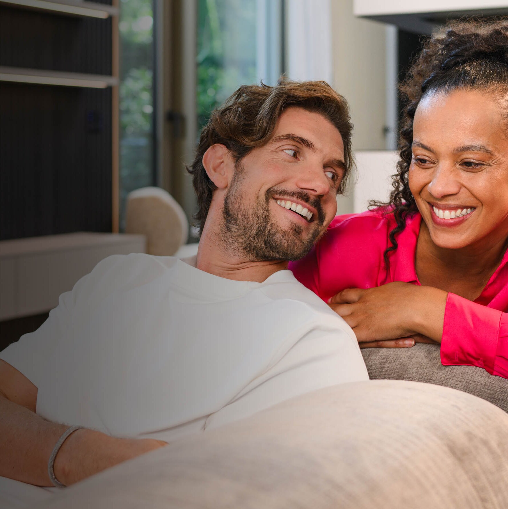 Zwei Personen sitzen auf einem Sofa und betrachten ein mobiles Gerät.