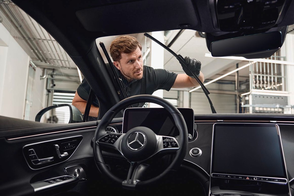 Original-Scheibenwischerblätter von Mercedes-Benz Innenansicht eines Mercedes-Benz-Fahrzeugs, in dem ein Techniker Original-Scheibenwischerblätter austauscht.