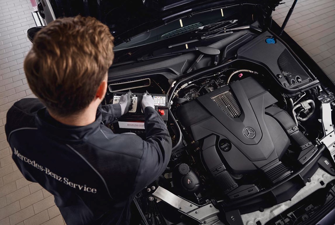 Original-Starterbatterien von Mercedes-Benz Motorservice in einer Werkstatt, bei dem der Austausch von Bauteilen unter Verwendung von Mercedes-Benz Originalteilen gezeigt wird.