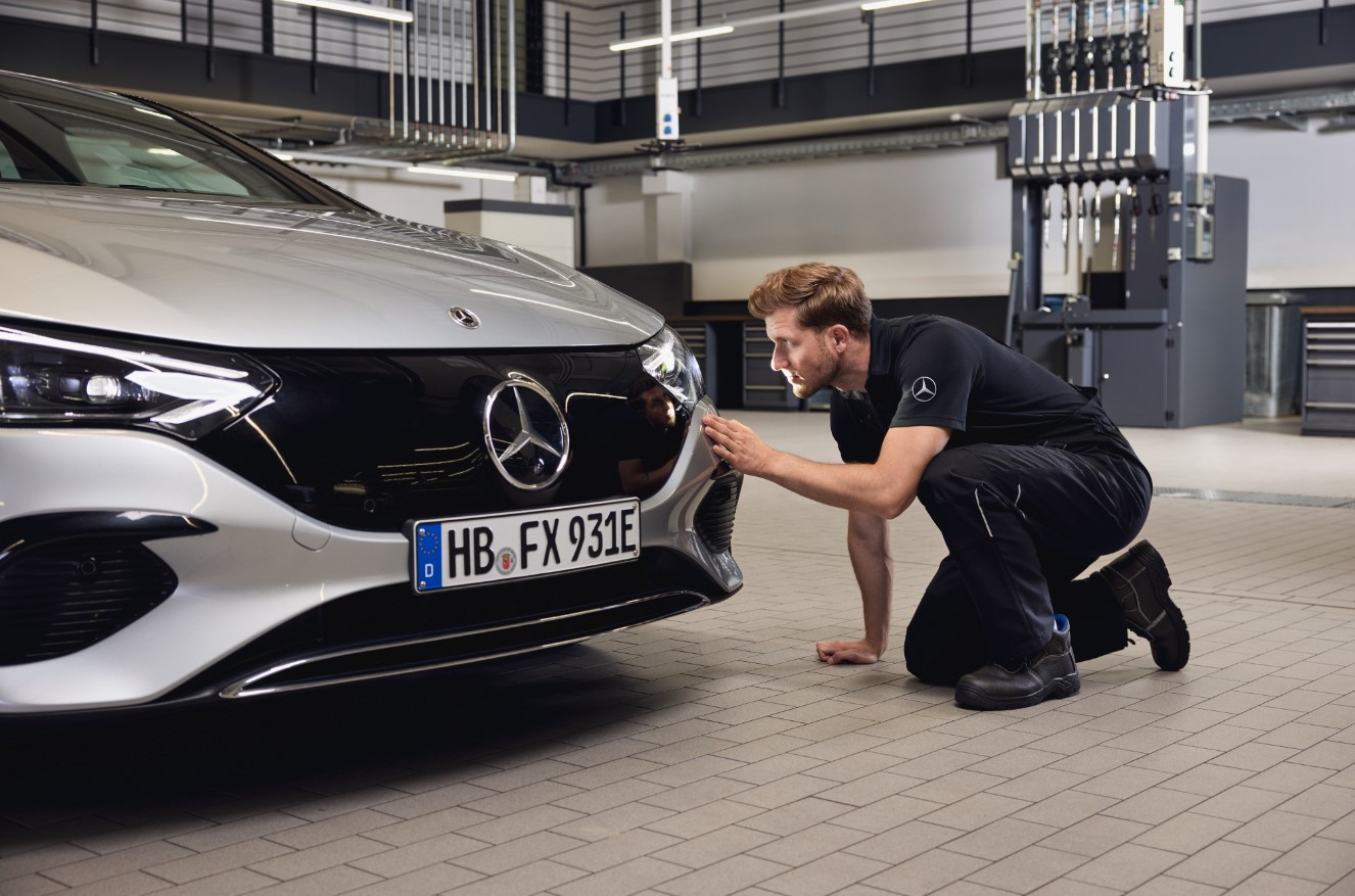 Original-Scheinwerferersatz von Mercedes-Benz Nahaufnahme der Fahrzeugfront eines Mercedes-Benz, an der ein Techniker eine gründliche Prüfung im Zusammenhang mit dem Einbau von Mercedes-Benz Originalteilen durchführt.