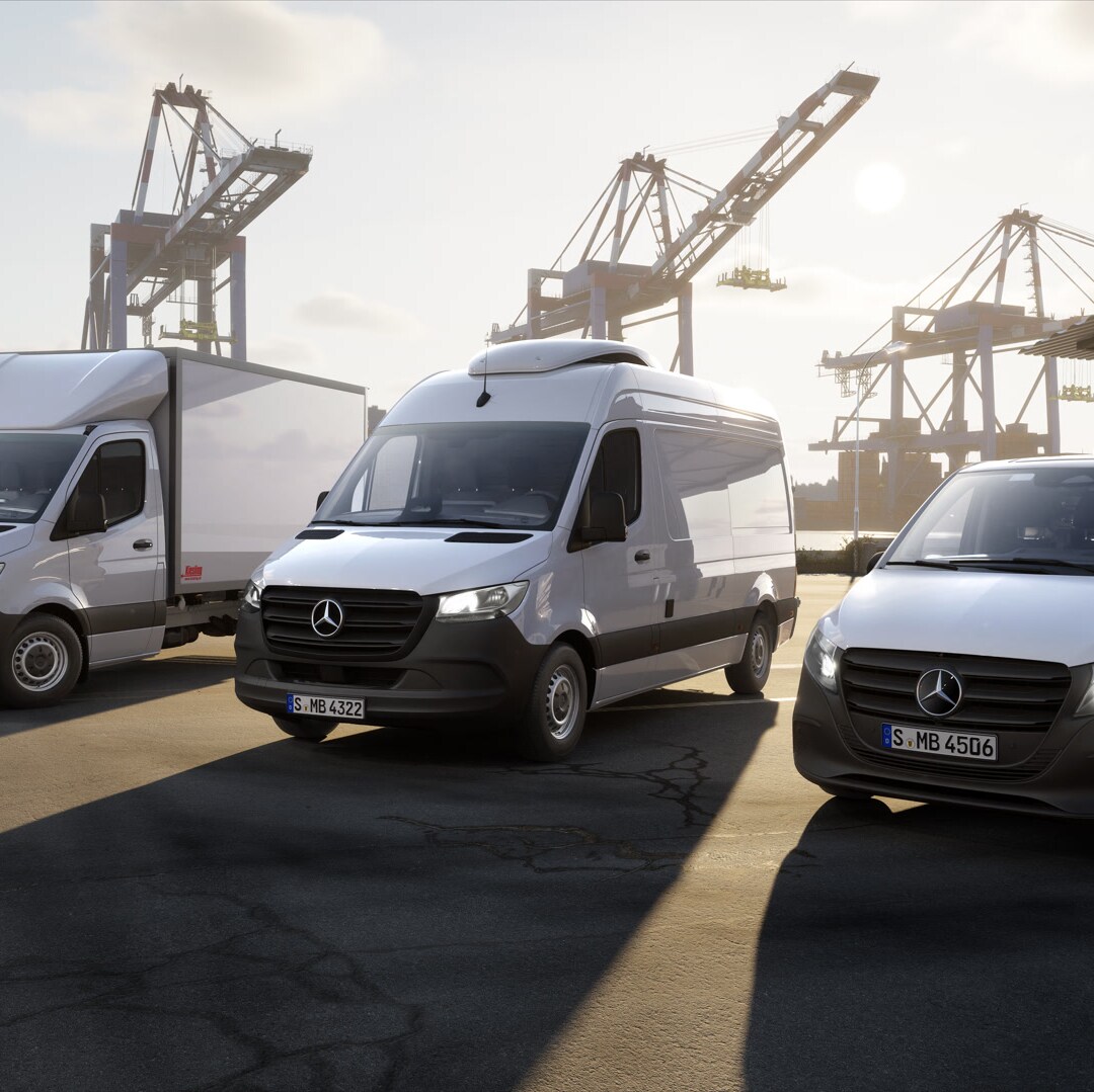 Drei Mercedes‑Benz Transporter stehen auf einem Containerterminal vor Hafenkränen. Zu sehen sind ein Fahrzeug mit Aufbau, ein Kastenwagen und ein kompakter Van im Logistikumfeld.