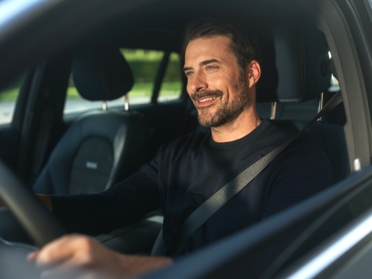 Ein Mann fährt in seinem Fahrzeug und genießt die digitalen Extras, welche die Fahrt komfortabler machen.