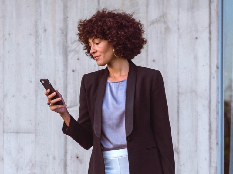 Eine Frau nutzt ihr Handy bzw. die digitalen Extras zur Verwaltung ihrer Anliegen.
