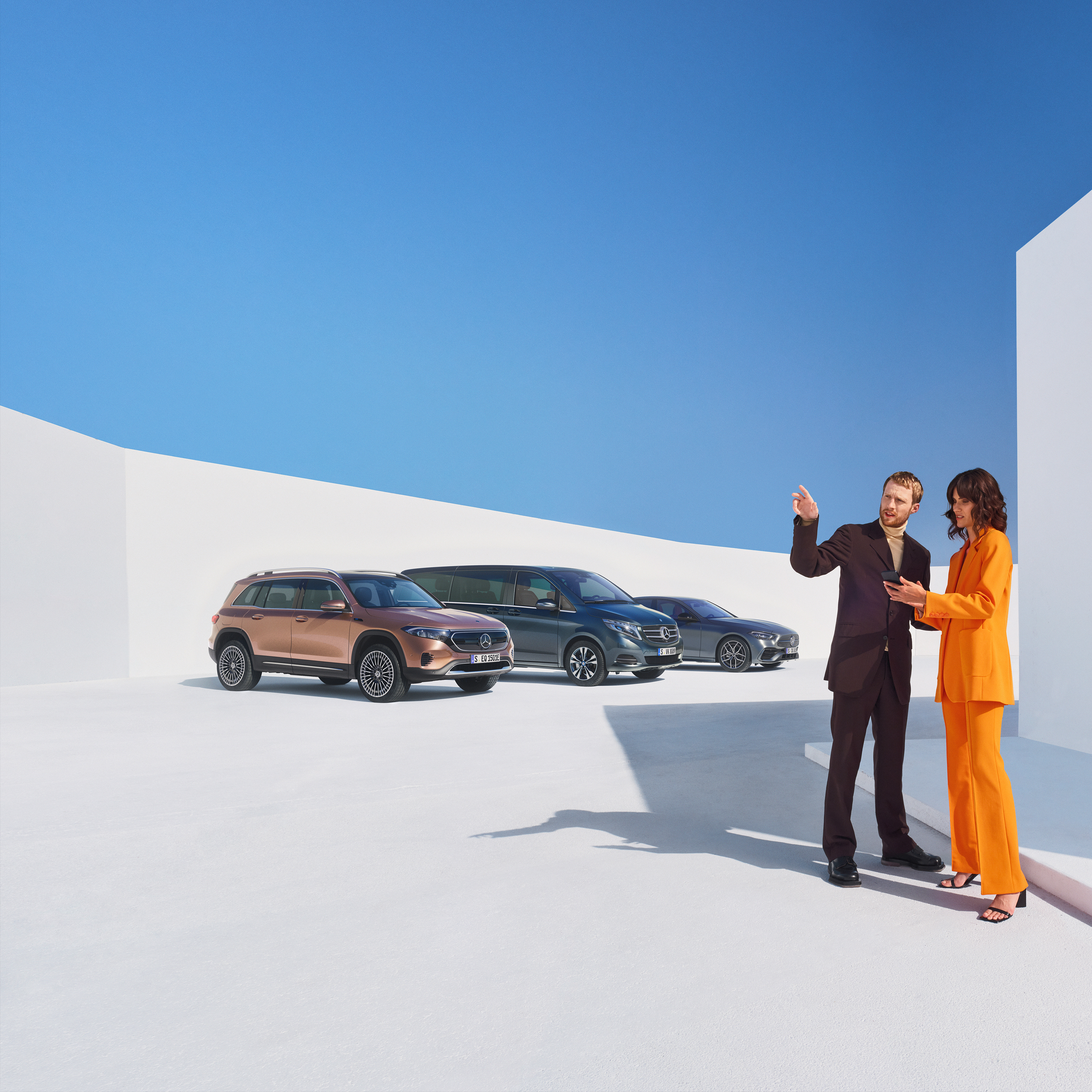 Business | Mercedes me Zwei Frauen unterhalten sich über Digitale Extras für Geschäftskunden. Im Hintergrund sind drei Mercedes-Benz Fahrzeuge zu sehen.