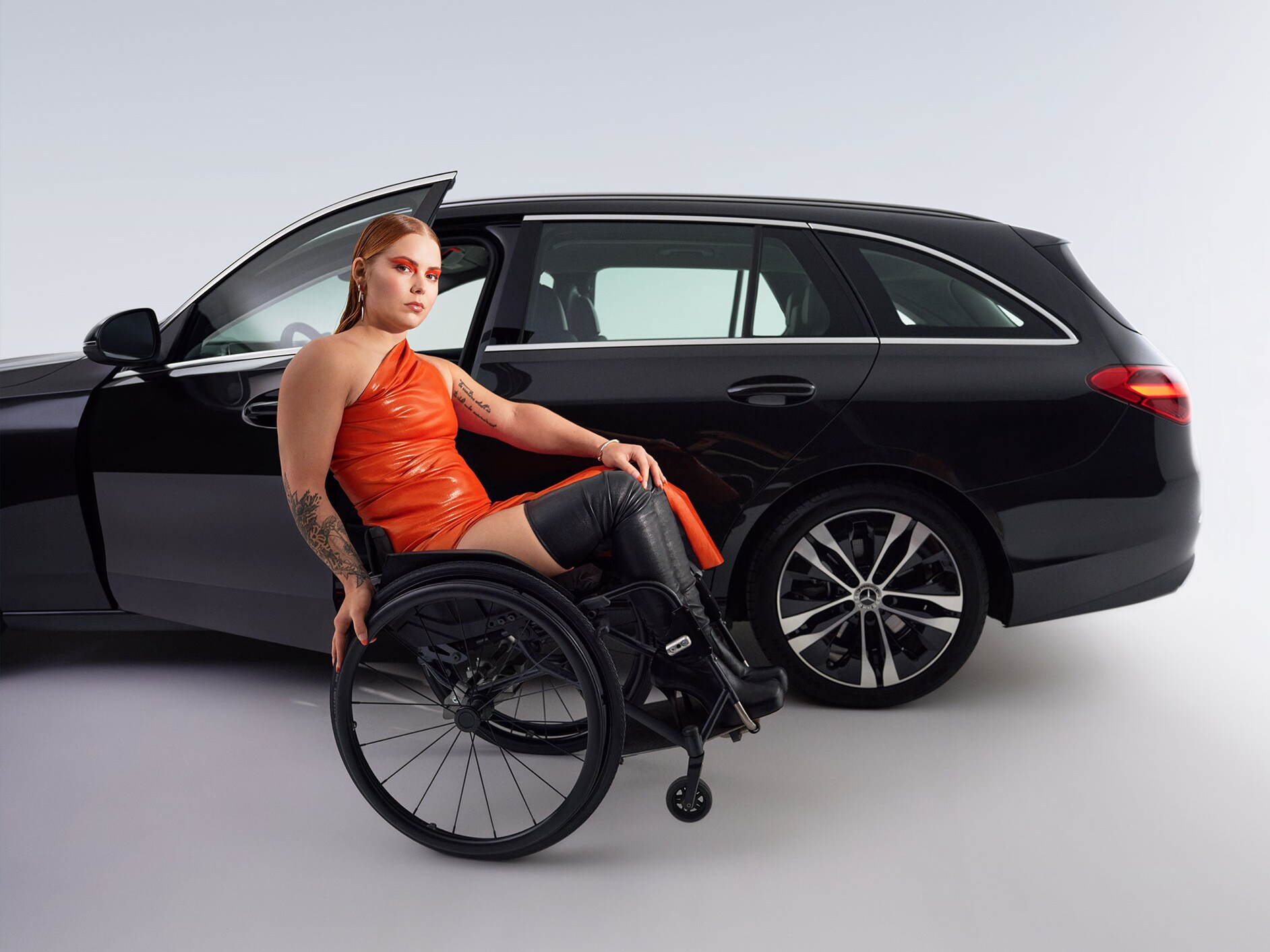 Das behindertengerecht umgebaute C-Klasse T-Modell in einer Seitenansicht und eine Frau im Rollstuhl.