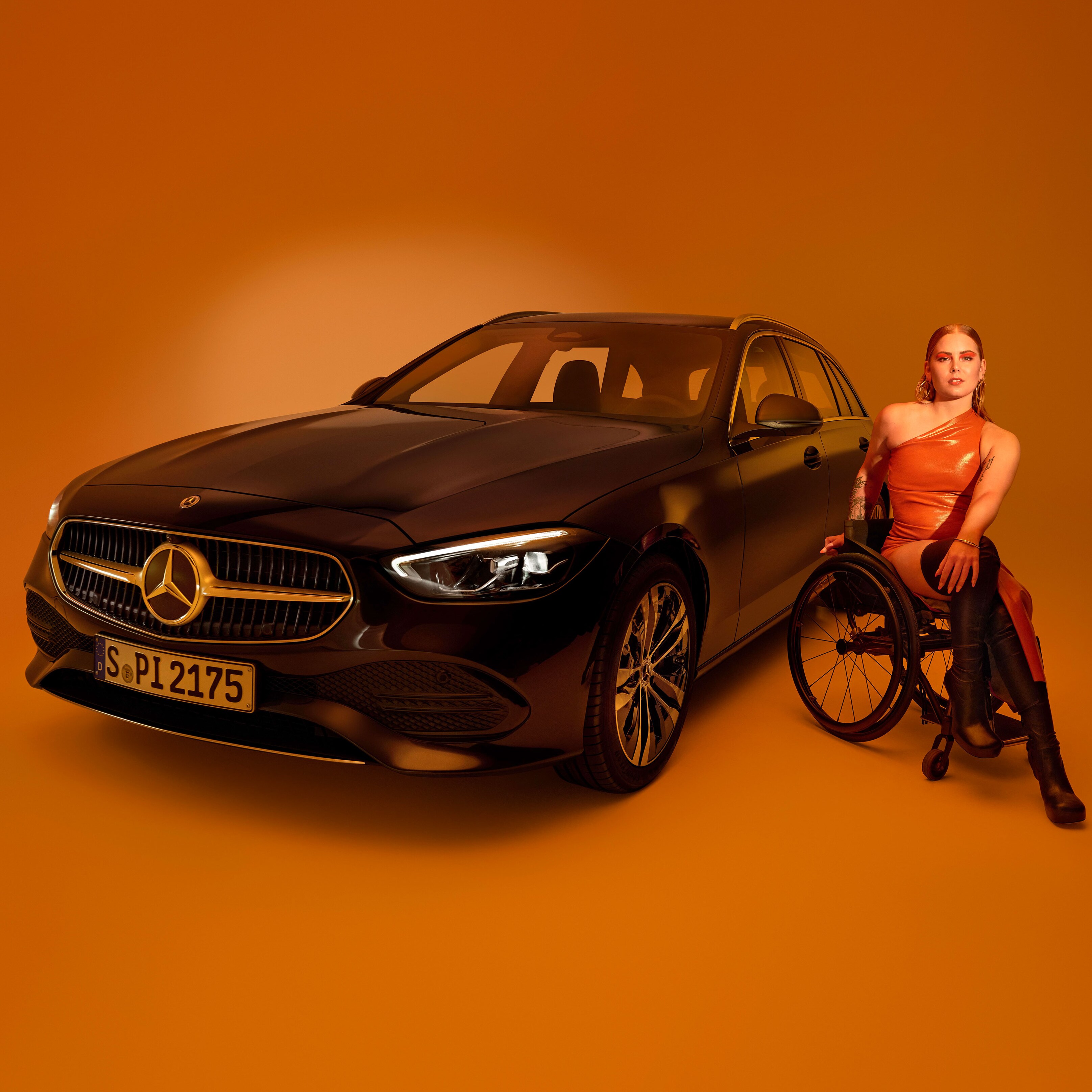 Das Exterieur einer als behindertengerechtes Auto umgebauten C-Klasse T-Modell und eine Frau im Rollstuhl.