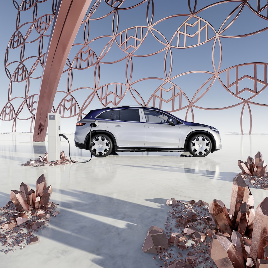 Seitenansicht des Mercedes-Maybach EQS SUV an der Ladestation, mit dem Maybach Markenlogo im Hintergrund.