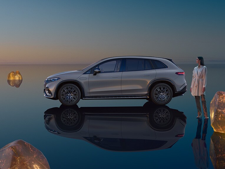 Der vollelektrische EQS SUV von Mercedes-EQ stehend in seiner EQS SUV-Welt mit spiegelnder Bodenfläche.