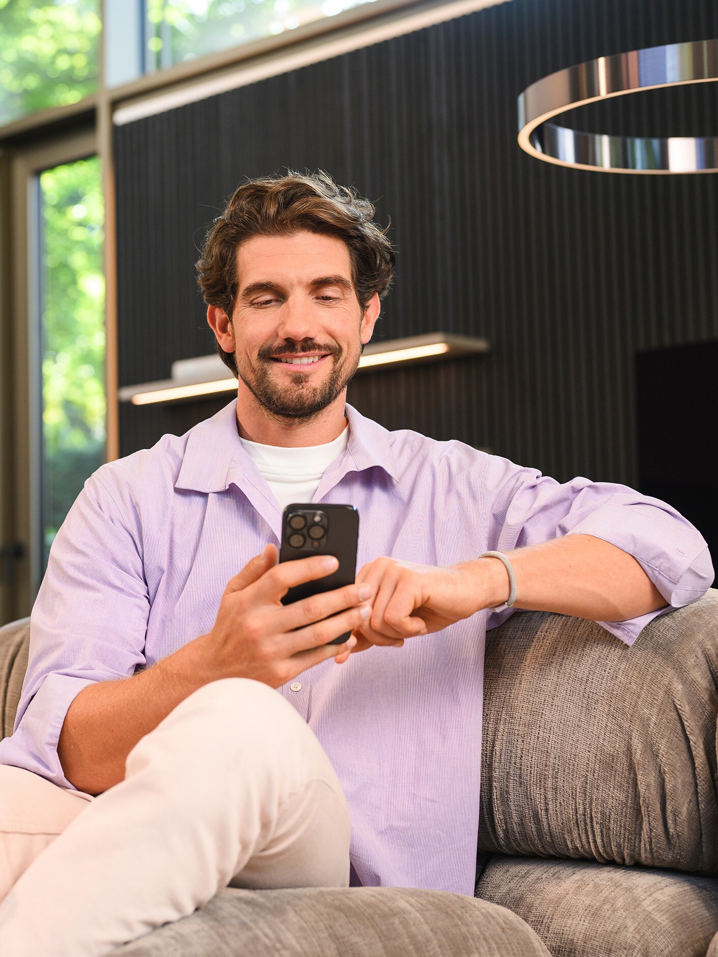 Eine Person sitzt auf einem Sofa und benutzt ihr mobiles Gerät.