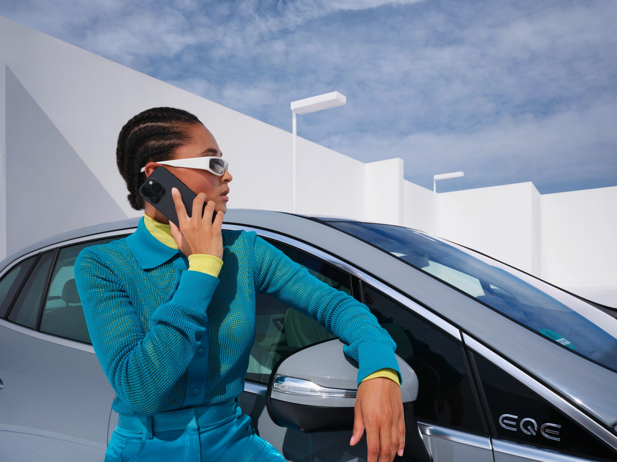 Eine Person, die sich mit dem Telefon in der Hand an ein Mercedes-Benz Fahrzeug lehnt.