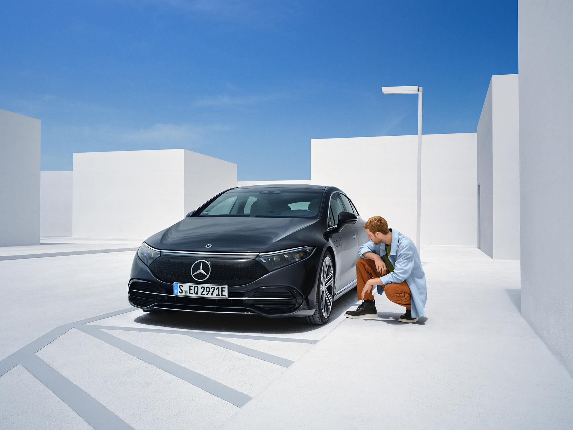 Unfallschaden | Mercedes-Benz Eine Person kniet neben ihrem Mercedes-Benz, um ihn zu überprüfen