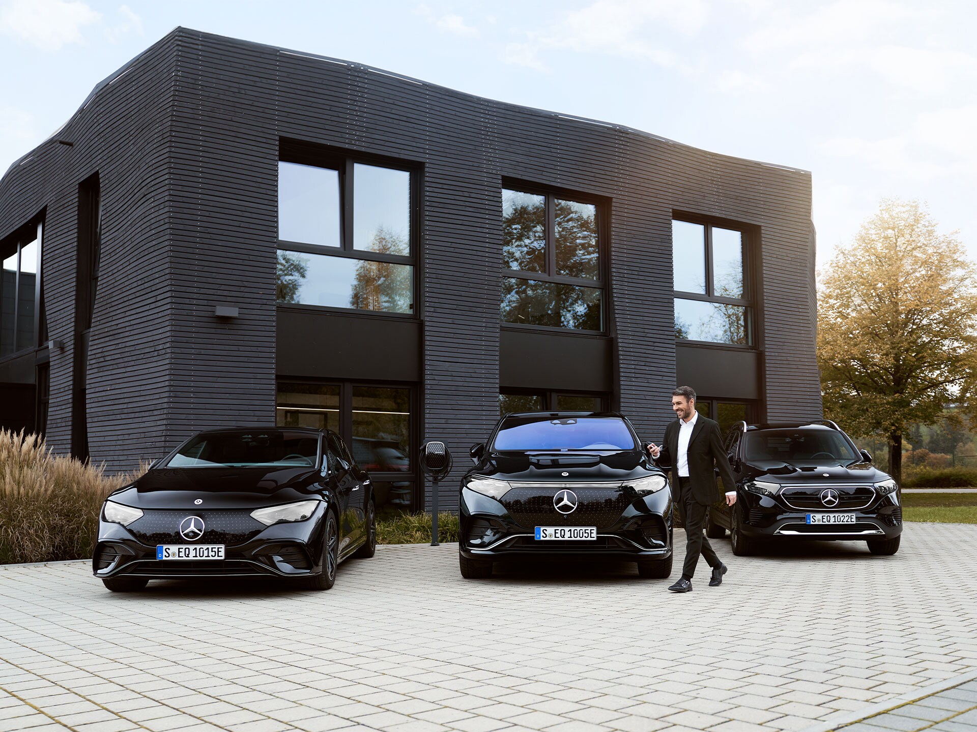 Drei Mercedes-Benz Elektroautos vor einem Bürogebäude.