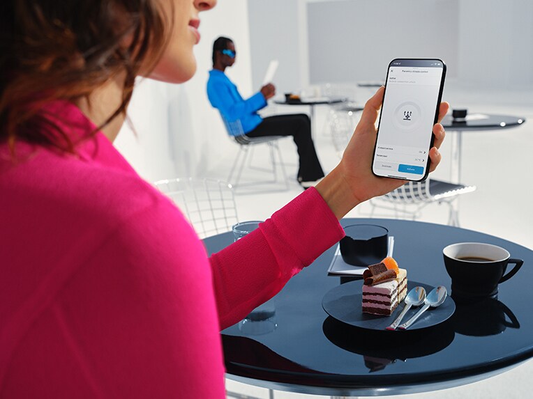 Eine Frau hält ihr Mobiltelefon in der Hand und nutzt die Mercedes-Benz App.