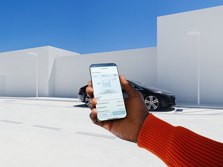 Eine Frau nutzt die Mercedes me App auf ihrem Smartphone, um sich mit Ihrem Mercedes-Benz zu verbinden.