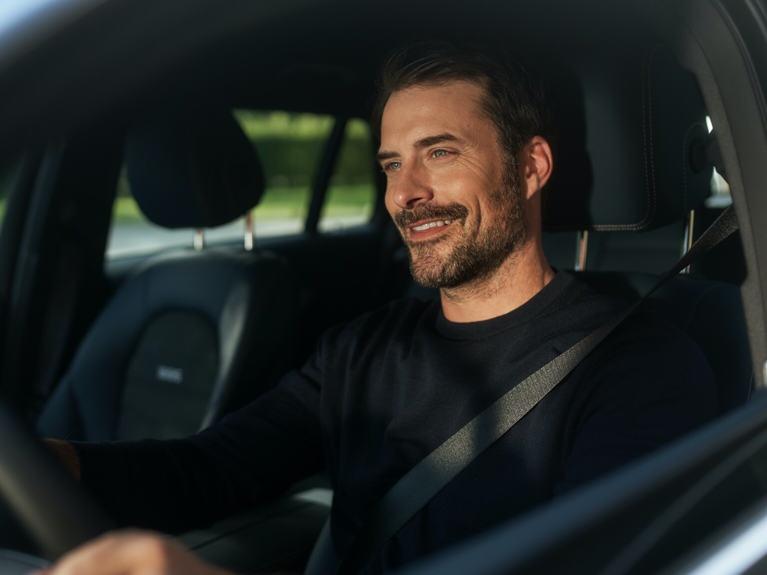 Ein Mann genießt in seinem Mercedes-Benz dank des Entertainment Packages unterbrechungsfreies Internetradio.