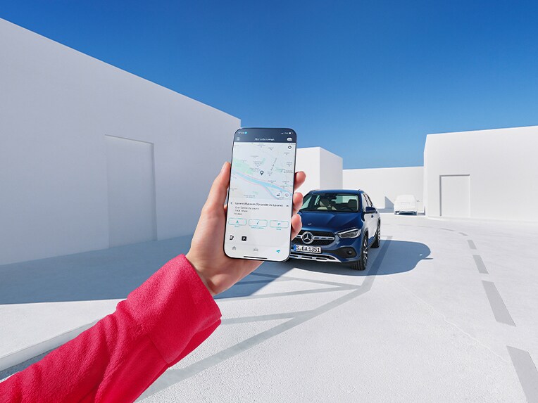 Mit der Mercedes me App können Kunden per Smartphone den Ladevorgang des E-Autos an ihrer Wallbox kontrollieren. Im Hintergrund lädt ein Mercedes-Benz EQE auf