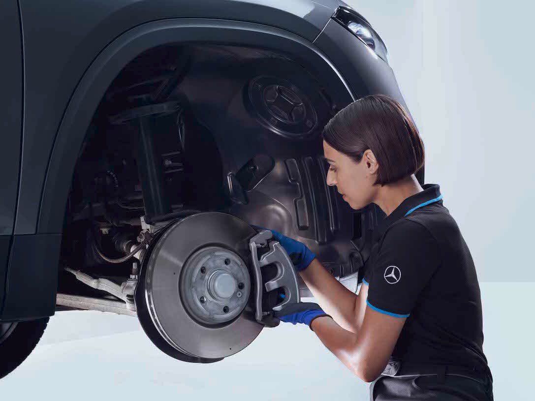 Eine Mercedes-Benz Technikerin überprüft die Bremsen eines Fahrzeugs.