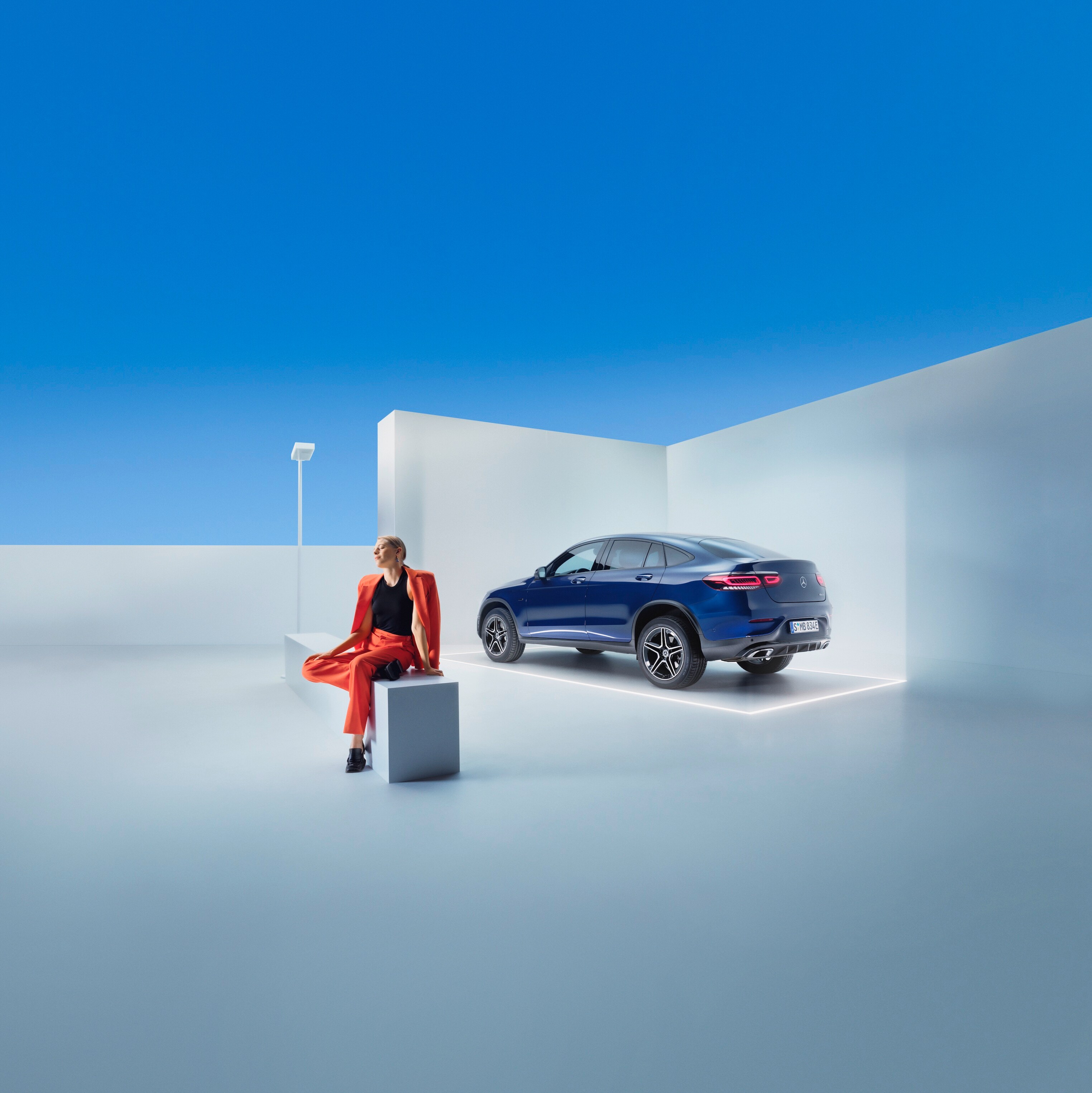 Eine Frau sitzt auf einer Bank vor einem Mercedes-Benz.