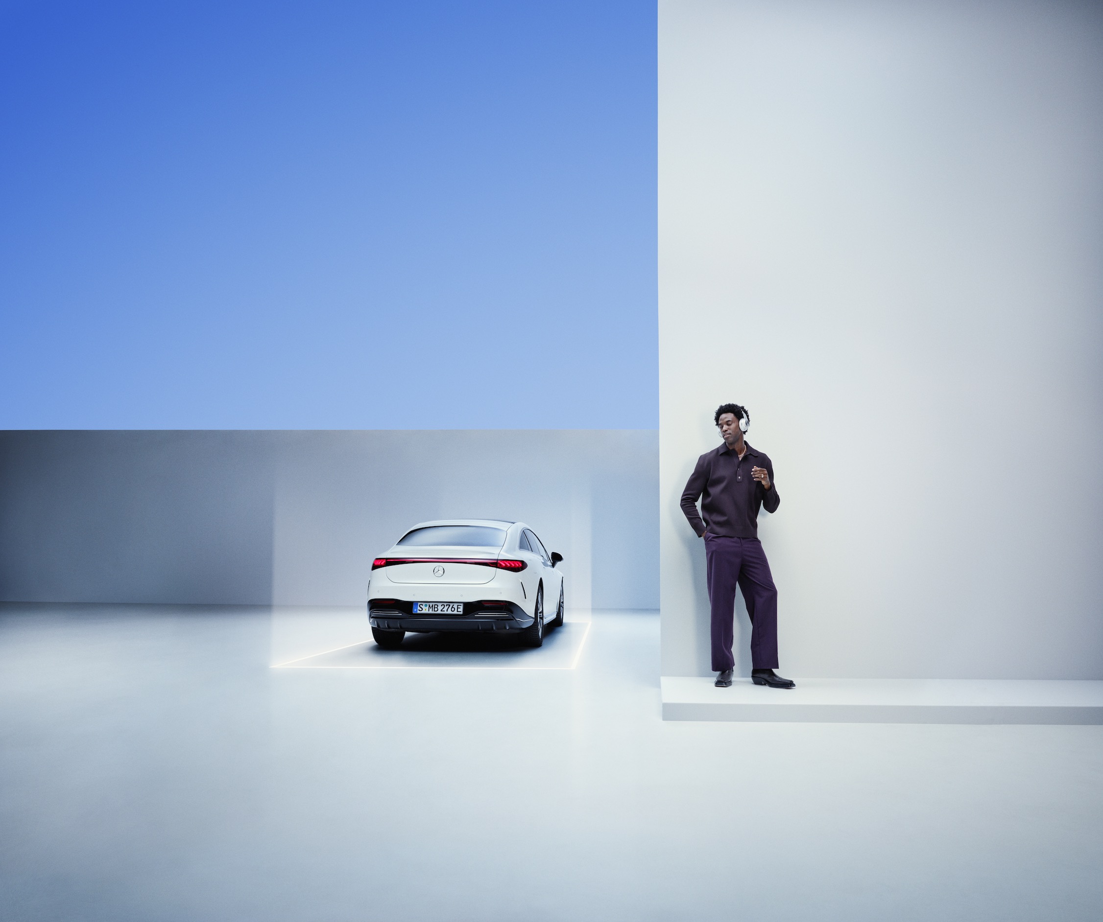 Ein Mann mit Kopfhörern lehnt an einer Wand neben seinem Mercedes-Benz. ServiceCare | Mercedes-Benz