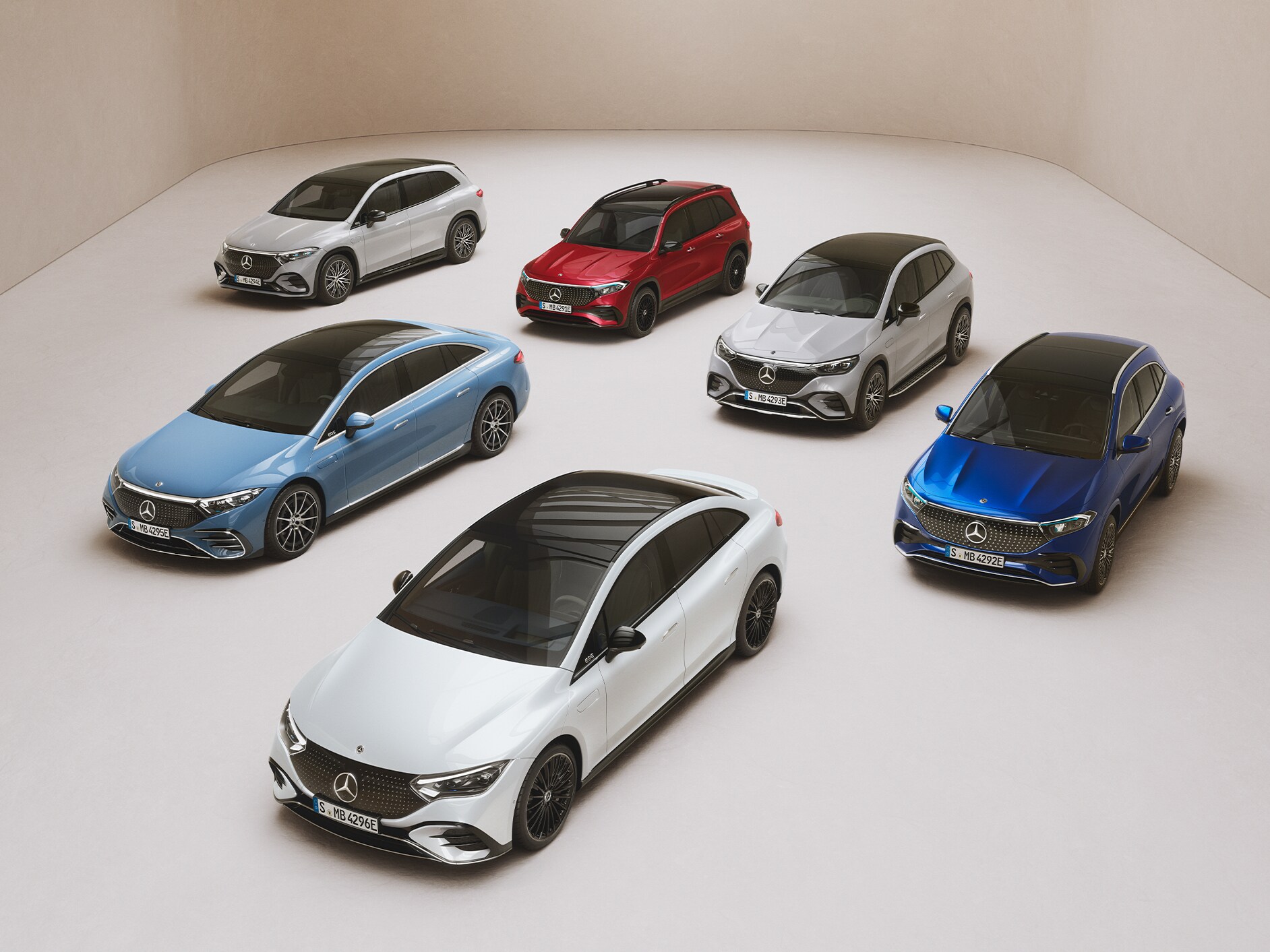 Die Modelle EQS Limousine, EQE Limousine, EQA, EQB und EQC stehen geparkt auf einer Spiegelfläche.