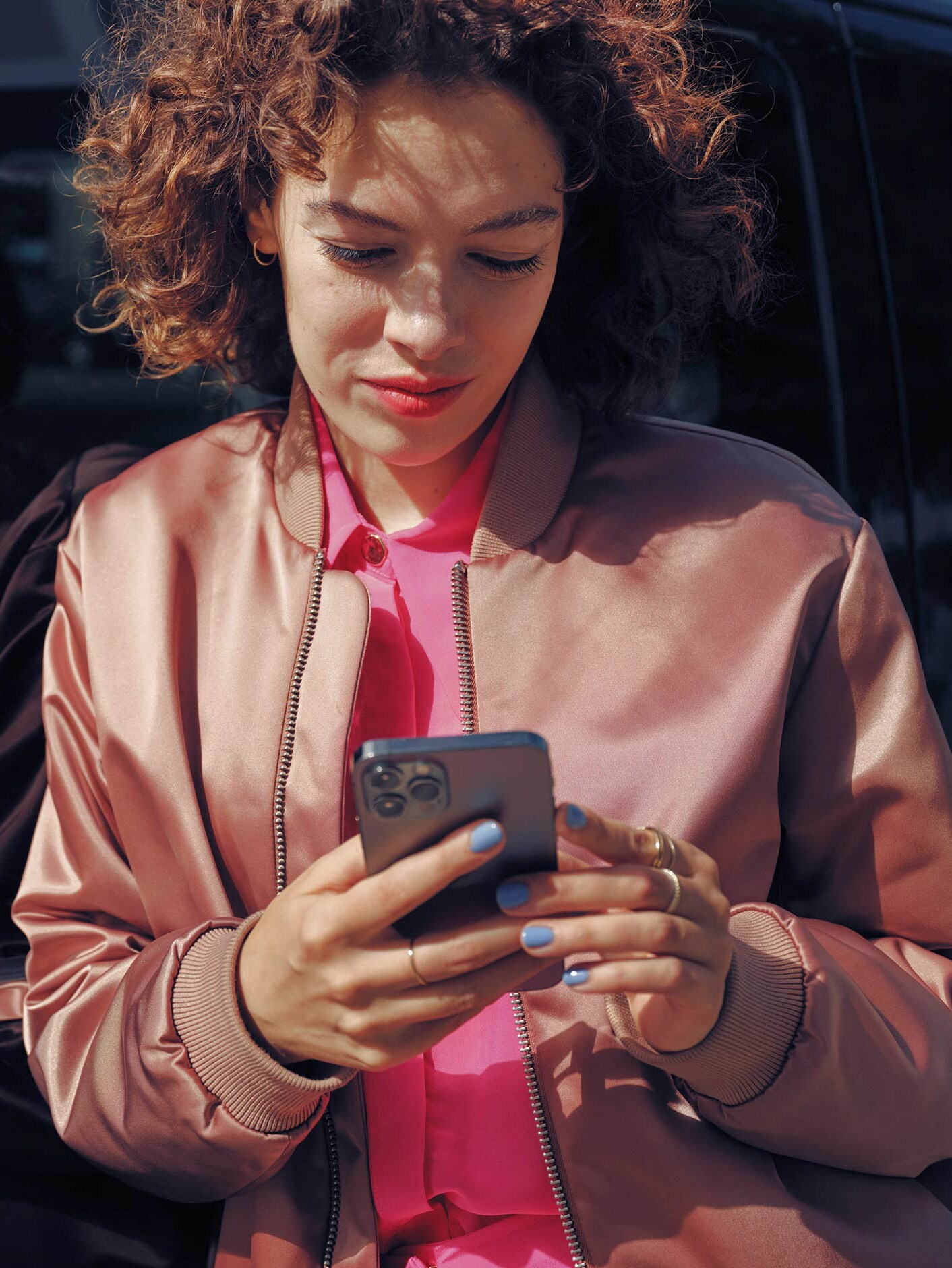 Frau am Mobiltelefon neben schwarzem Mercedes-Benz EQV-Van