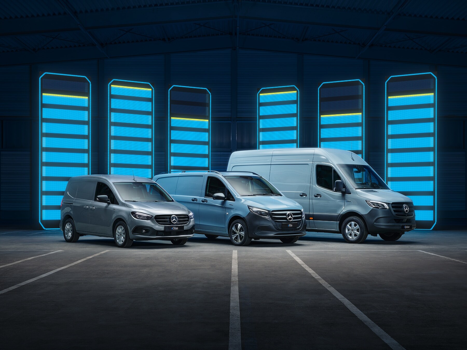Die Elektrotransporter-Modellpalette von Mercedes-Benz, ausgestellt in einer futuristischen Lagerhalle mit beleuchteten Ladestationen