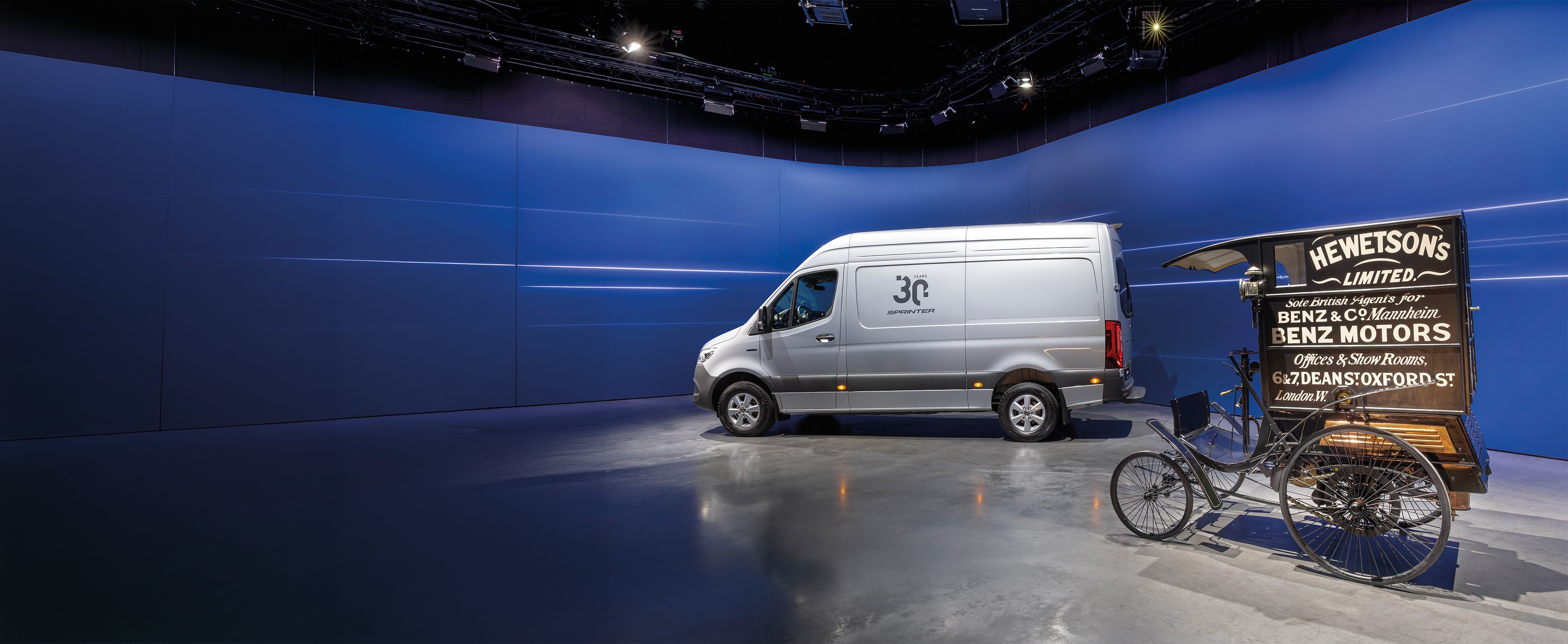 Geschichte | Nutzfahrzeuge | Mercedes-Benz Mercedes-Benz Sprinter und historischer Benz Lieferungs-Wagen, ausgestellt in einem modernen Showroom