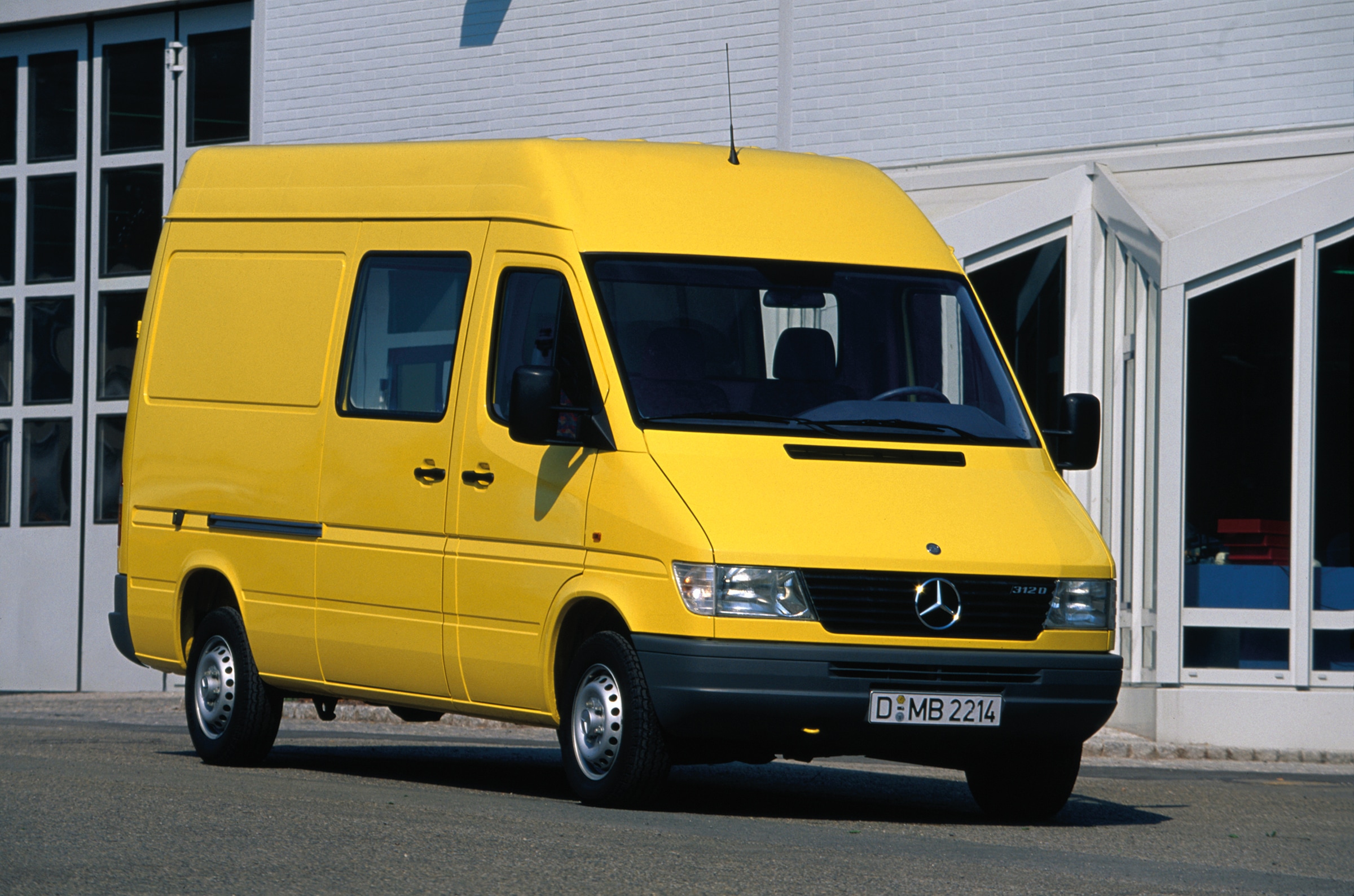 Die erste Generation der Mercedes-Benz Sprinter | Geschichte der Nutzfahrzeuge | Mercedes-Benz Ein Sprinter der ersten Generation, der vor einer Industriehalle geparkt ist