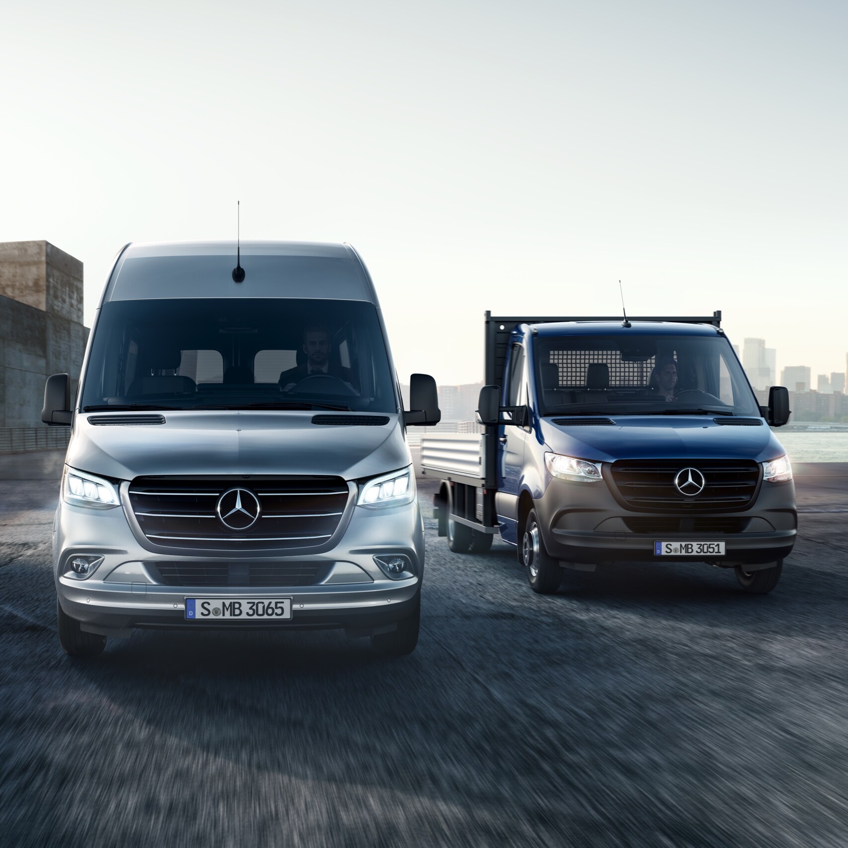Der Mercedes-Benz Sprinter als Pritsche und Kastenwagen stehen nebeneinander vor einem modernen Gebäudeensemble.