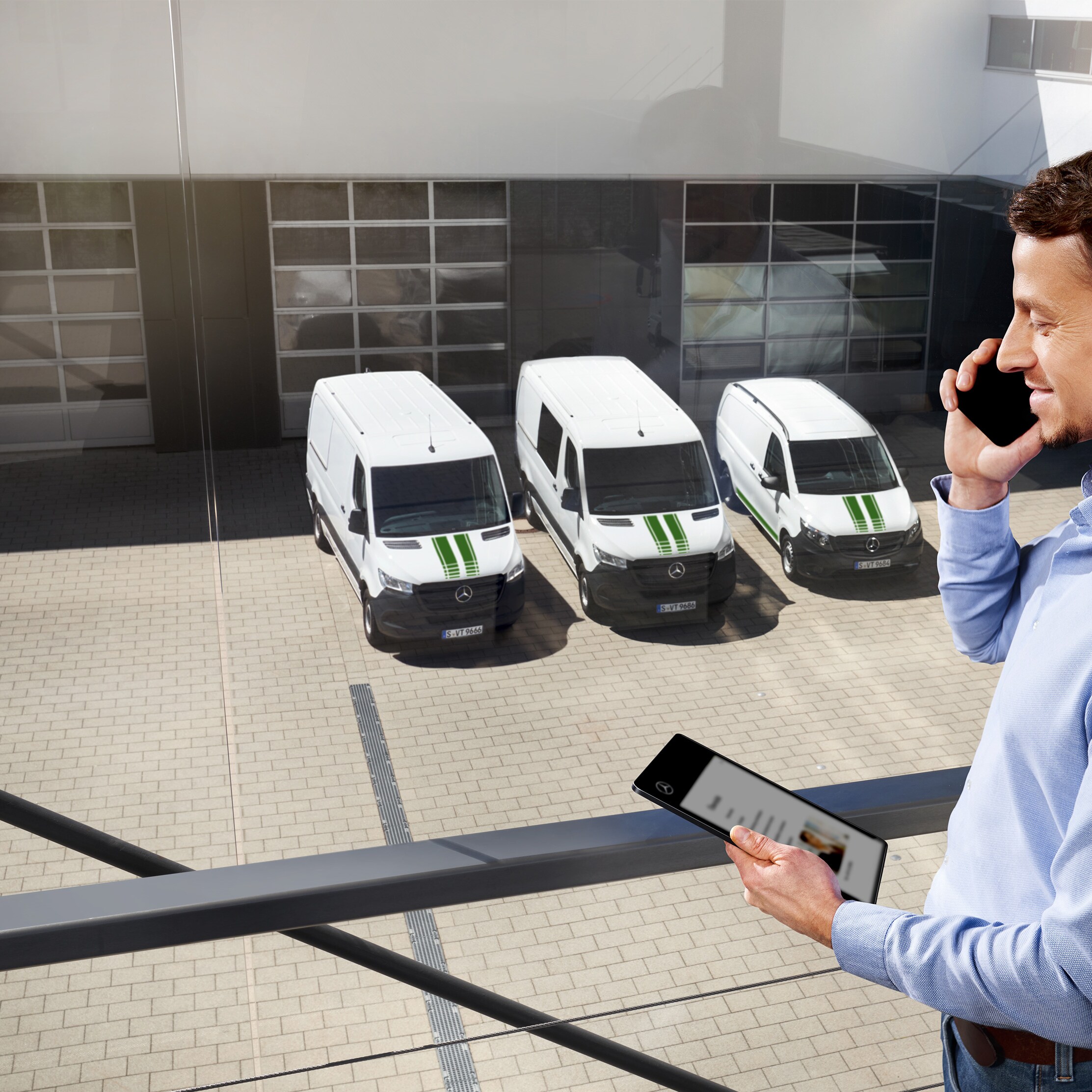 Customer on the phone in front of a fleet of white Mercedes-Benz vans.