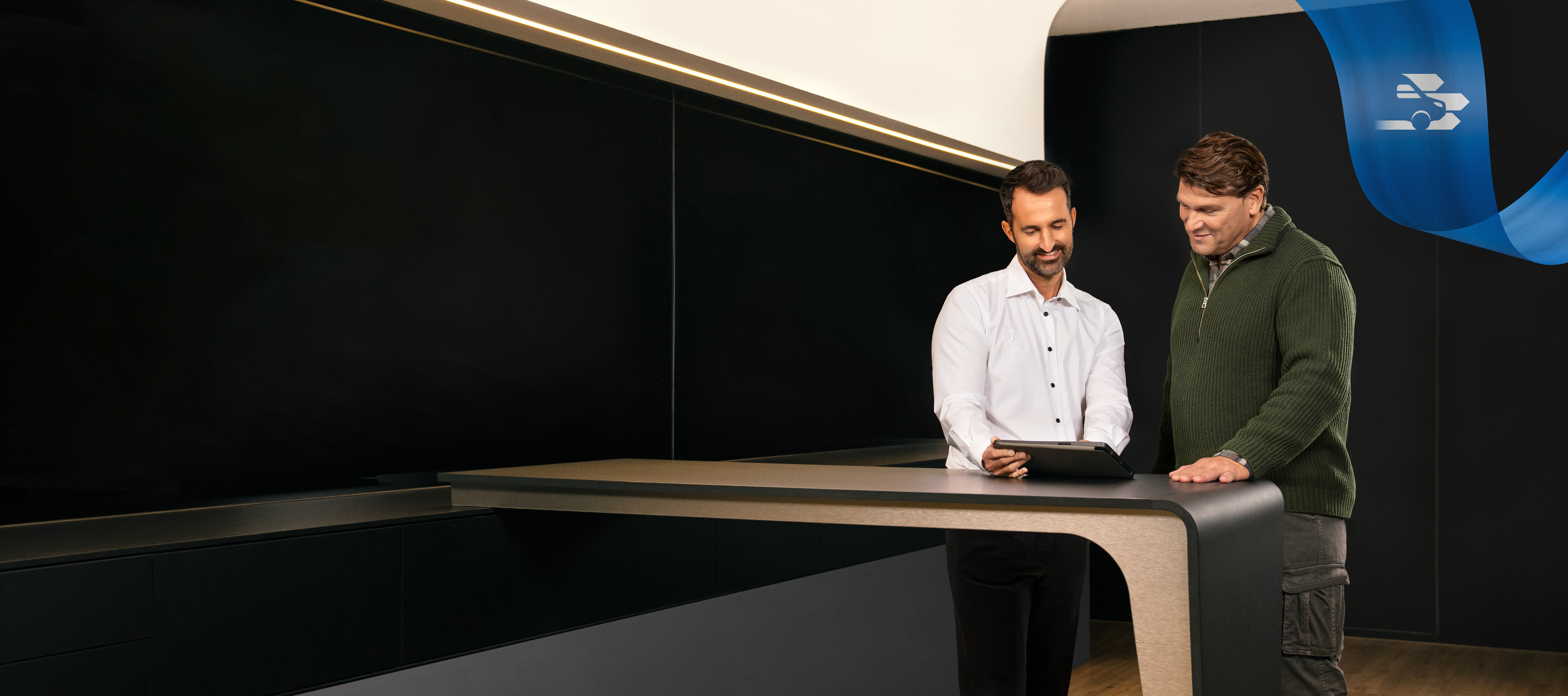 Mercedes-Benz | Komfort | Service-Partner Zwei Männer stehen im Büro eines Mercedes-Benz Service-Partners und diskutieren über etwas, das sie auf einem Tablet gesehen haben