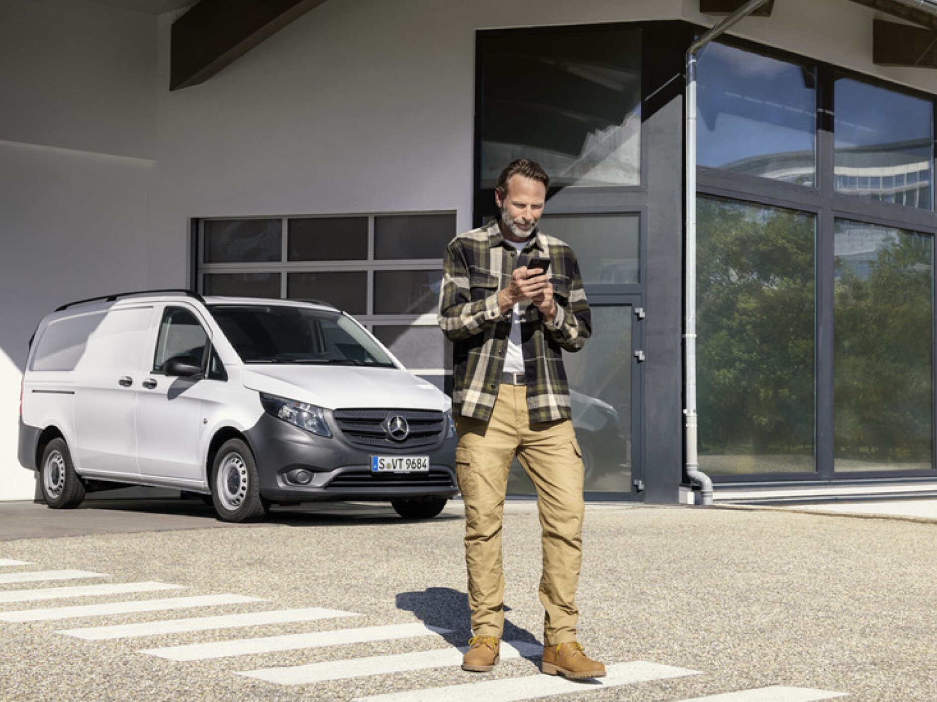 A person with a smartphone in front of a Mercedes-Benz Vito.