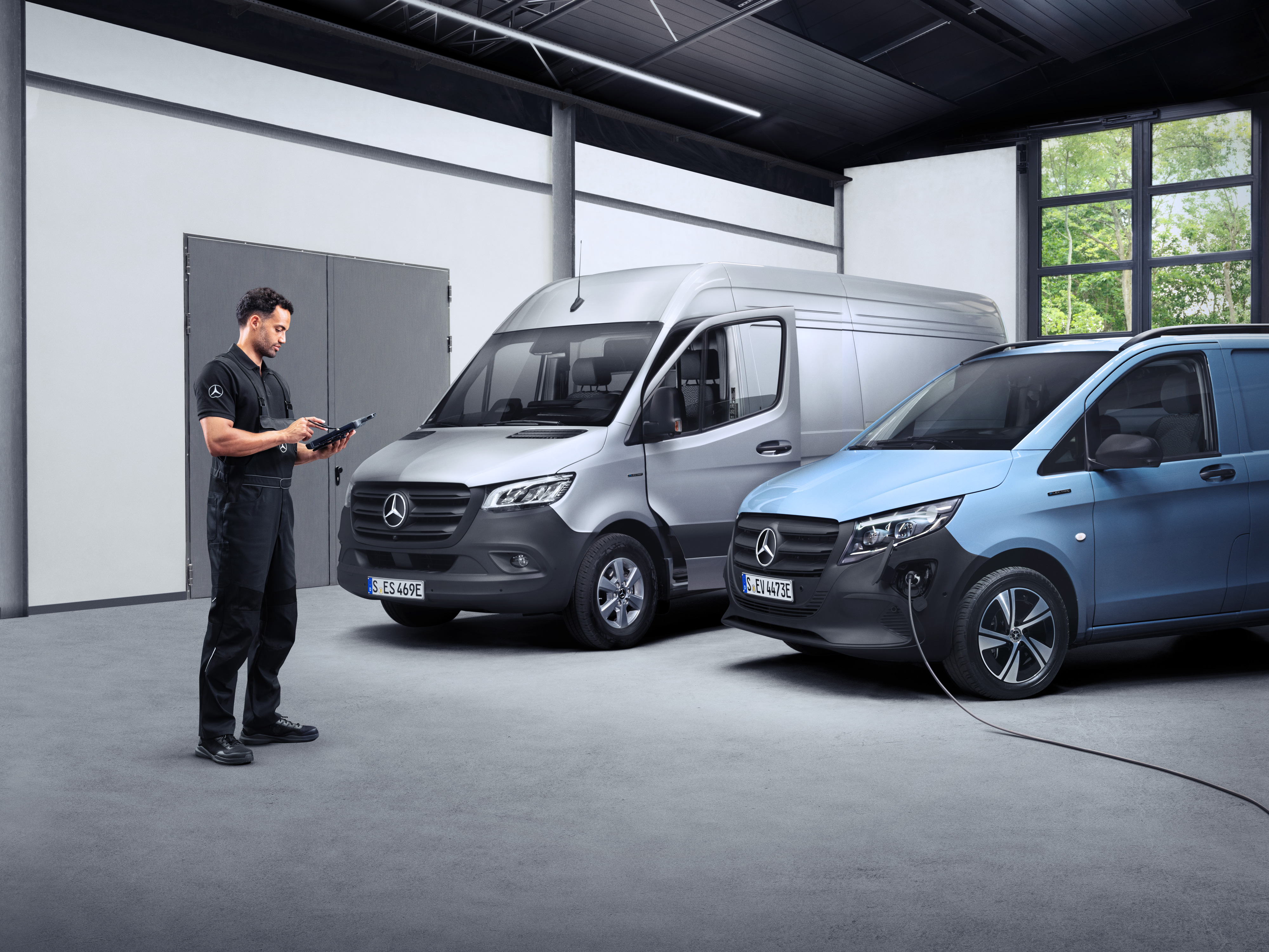 Mercedes-Benz | ServiceCare Transporter Ein Techniker arbeitet mit einem Tablet vor zwei Elektrotransportern