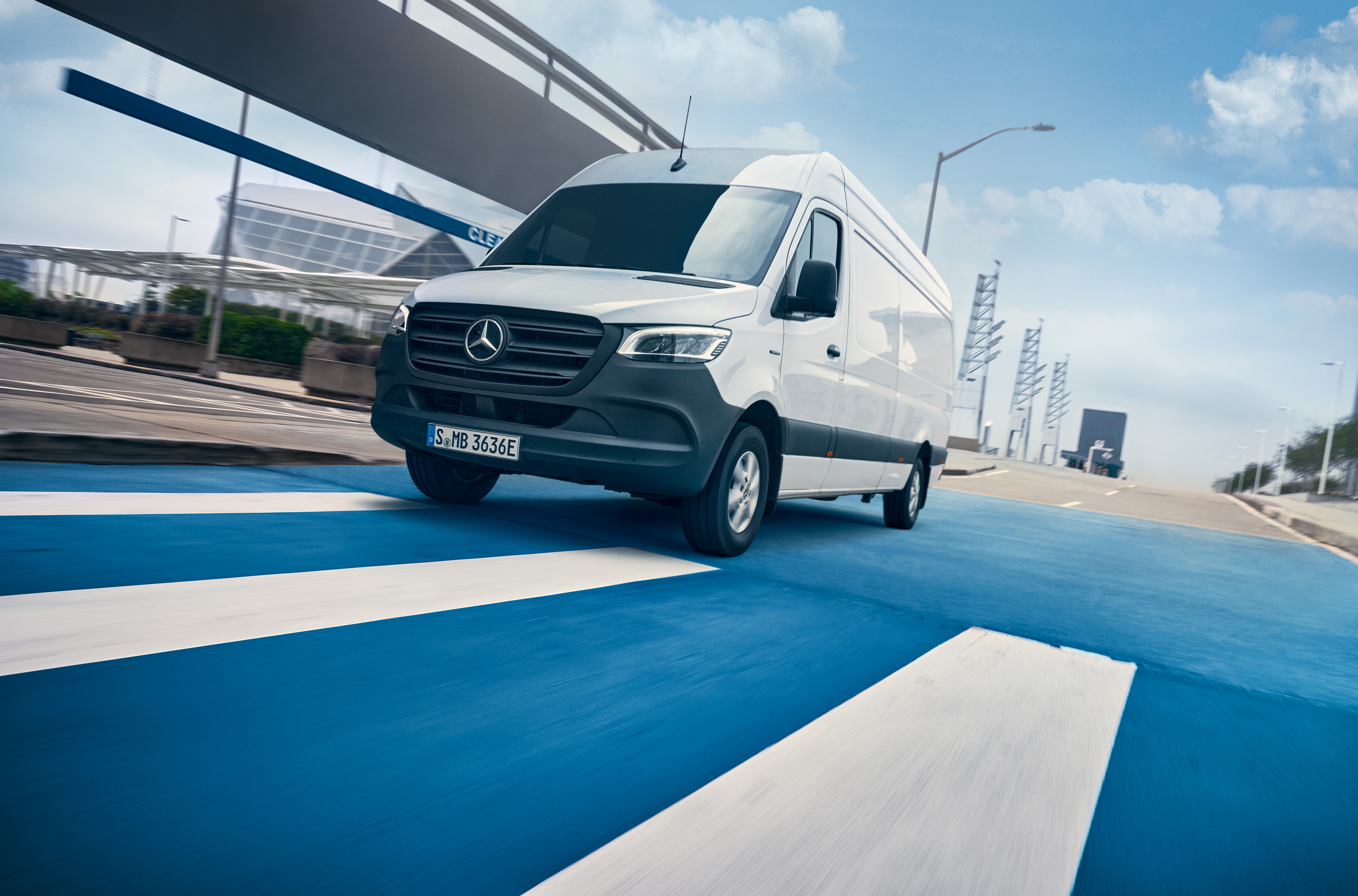 Mercedes-Benz | ServiceCare Transporter | Wartungspaket Ein weißer Mercedes-Benz Sprinter fährt auf einer Straße durch eine Stadt.