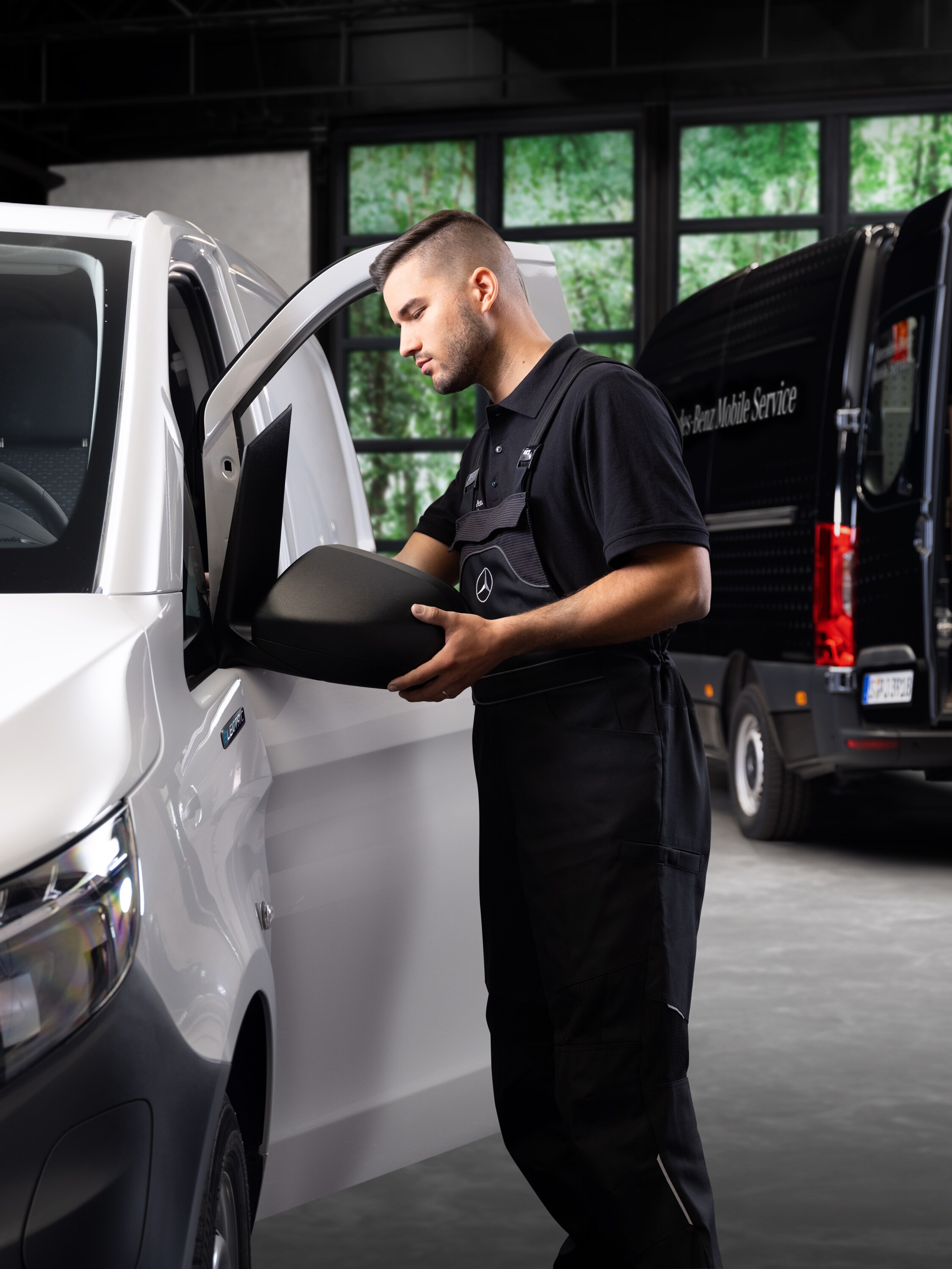 Ein Techniker tauscht einen Außenspiegel an einem weißen Mercedes-Benz Vito aus.