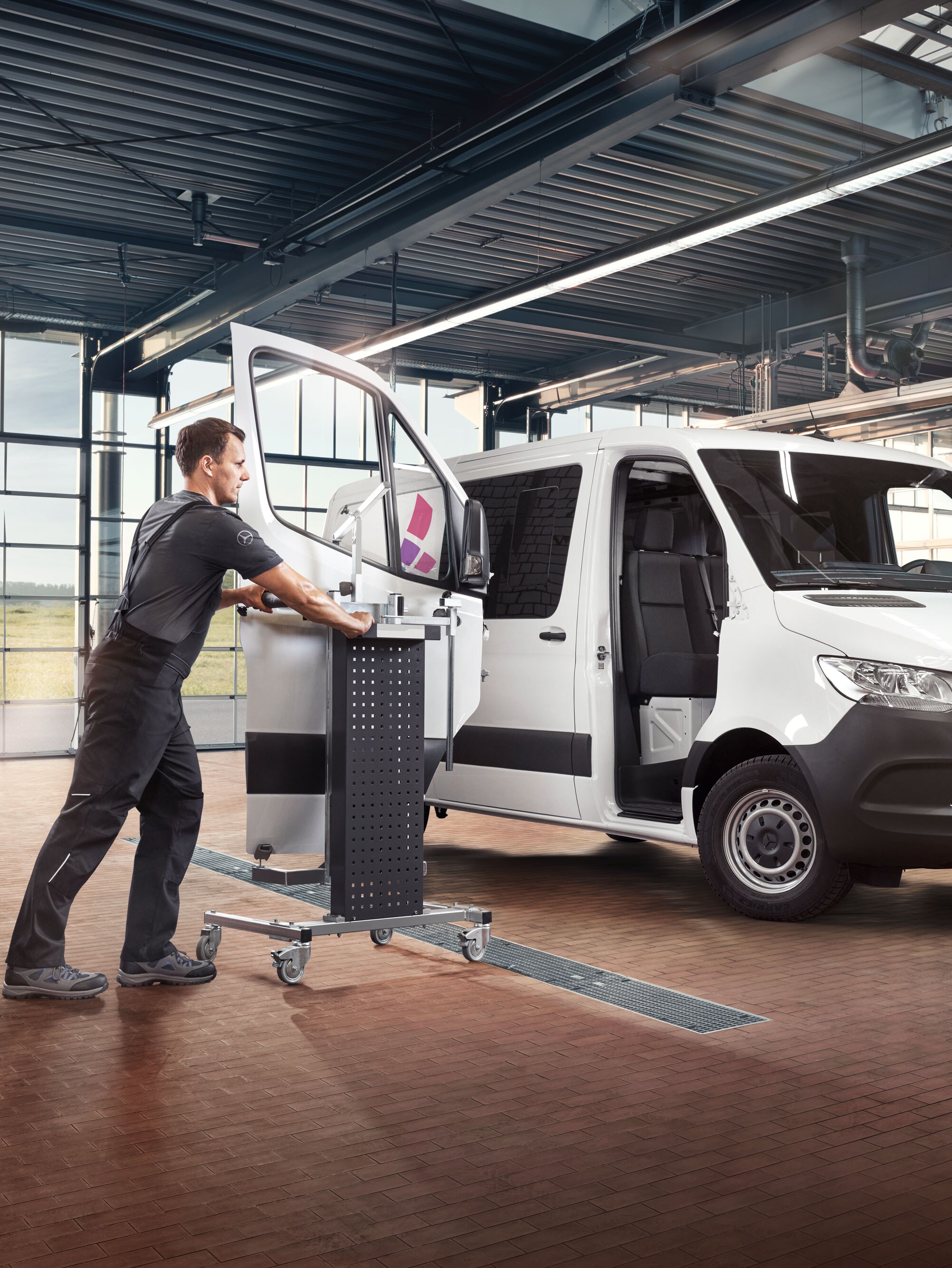 Mechaniker beim Einbau der Tür eines weißen Mercedes-Benz Sprinter.